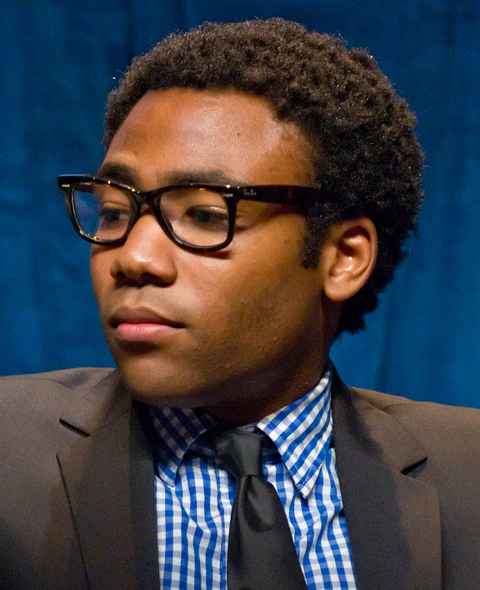 Donald Glover, a young African-American man wearing a suit and glasses. 