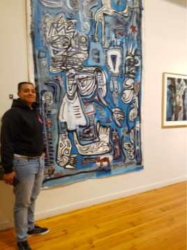 Engish instructor Kisha Quesada Turner, an African-American and Latinx woman, stands in front of a painting. 
